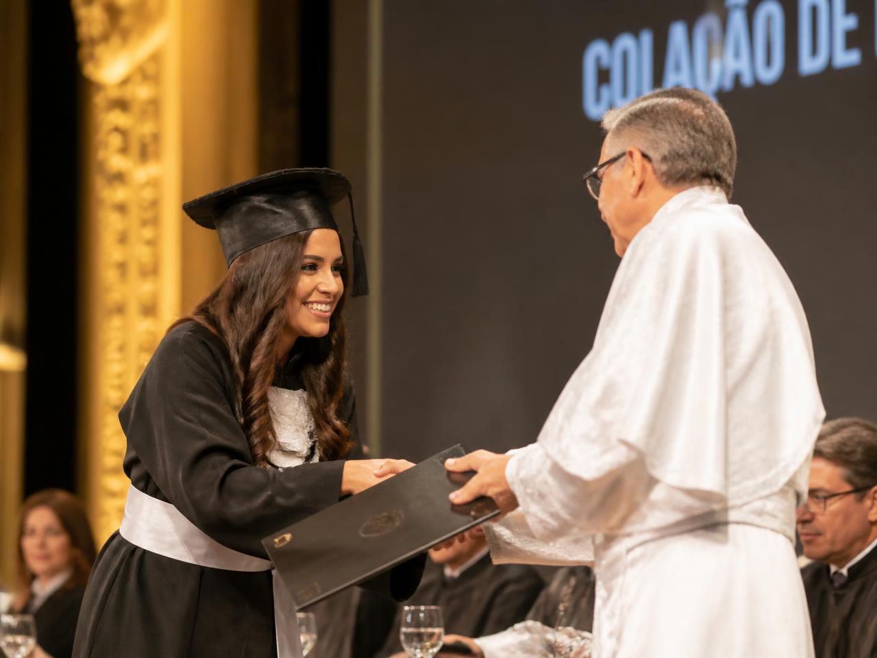 Reitor entregando diploma à formanda